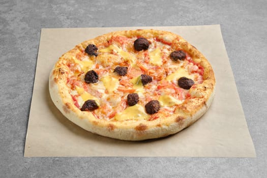 Top view of pizza with beef meatballs, cheddar and tomato slices on parchment paper