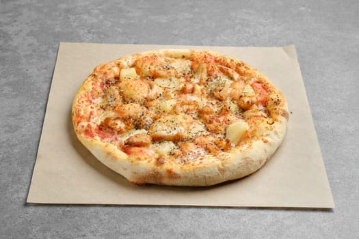 Pizza with chicken and pineapple on parchment paper