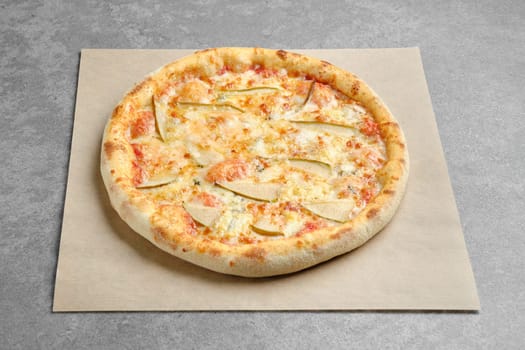 Pizza with blue cheese and slices of pear on parchment paper