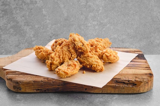 Deep fried chicken wings in breading on wooden serving board