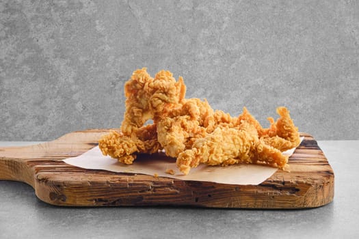 Deep fried chicken nuggets in breading on wooden serving board