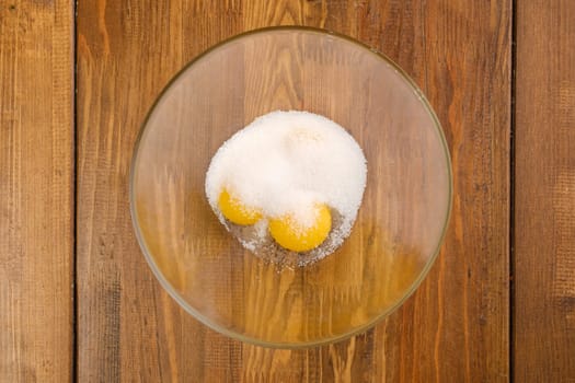 Top view of eggs and sugar in a glass bowl