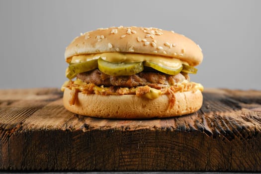 Beef burger with pickled cucumber and onion crumbs front view