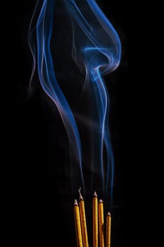 Smoke from incense in movement on a black background. It is abstract.