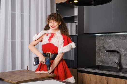 Smiling snow maiden installing hinges on kitchen cabinet door