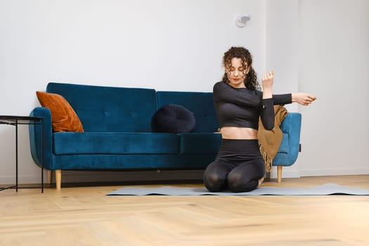 Young woman warming up arm muscles before doing fitness exercises at home
