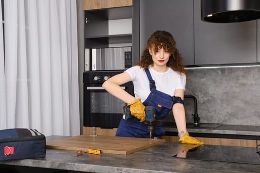 Young woman installing hinges on kitchen cabinet front