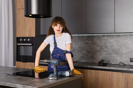 Pleased woman in overalls has finished assembling kitchen furniture
