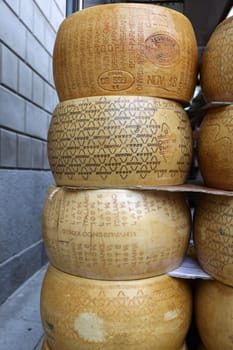 Cremona, Italy - September 7, 2022: Whole wheels of Parmigiano Reggiano cheese sold at a street stall during the farmers market in Cremona, Lombardy, Italy