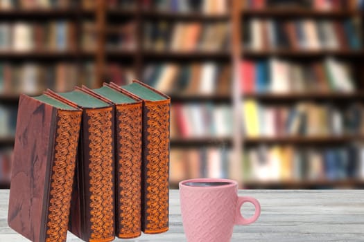 Books backgrounds. Closeup of antique books with a coffee mug on a wooden table over abstract blurred bookshelf in library. Education concept. Teacher day.