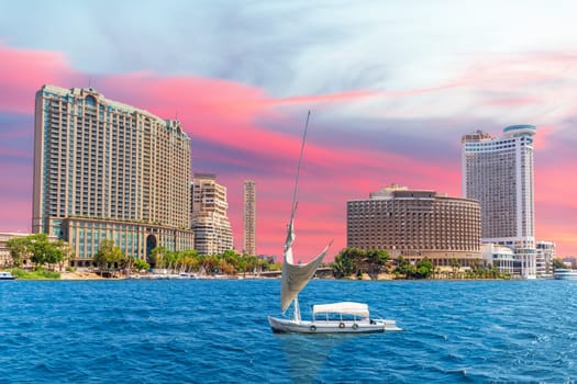 Nile river with fancy yacht and sunset sky over fashionable buildings of Cairo, Egypt.