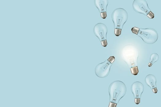 Light bulbs on a blue background and one creative glowing light bulb. Creative idea, concept. Electricity and think differently.