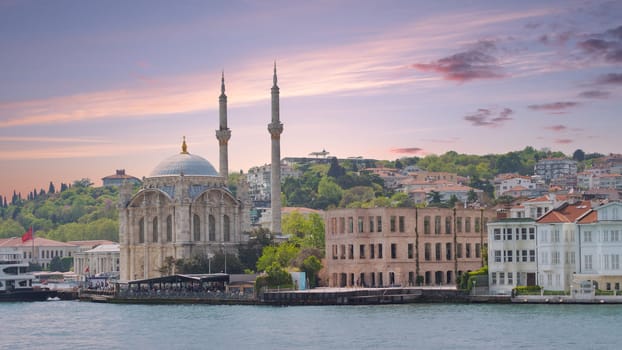 Istanbul, Turkey - May 8, 2023: View from Bosphorus Strait overlooking Ortakoy Mosque and redeveloped Esma Sultan Mansion, currently a Cultural center, Ortakoy pier square before sunset