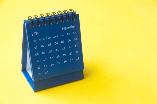 September 2024 blue desk calendar on yellow cover background with customizable space for text. Copy space and calendar concept.