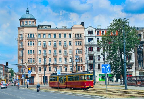 red tram going on street of Lodz. Popular touristic attraction and destination. Colored tramway going along city. Modern passenger transportation