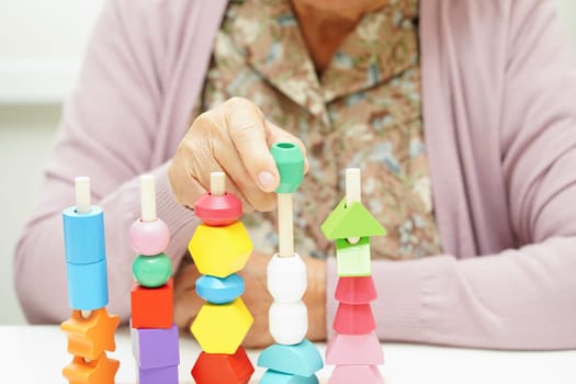 Asian elderly woman playing puzzles game for treatment dementia prevention and Alzheimer disease.