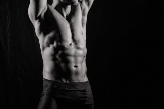 Confident, attractive shirtless muscular young man topless in a studio