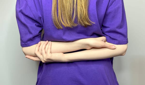 the girl folded her hands behind her back - a closed pose