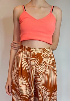 the body of a slender girl in a bright top with a bare stomach