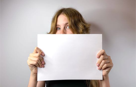 a young girl holds a white sheet of paper in her hands