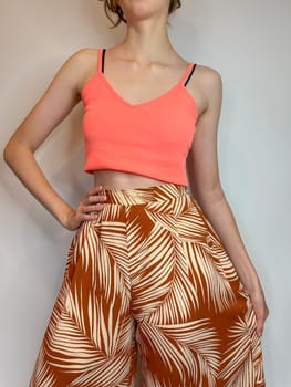 the body of a slender girl in a bright top with a bare stomach