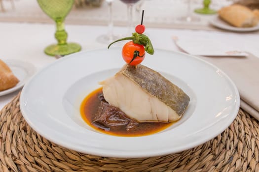 Confit of codfish loin topped with cherry tomato brochette. Closeup