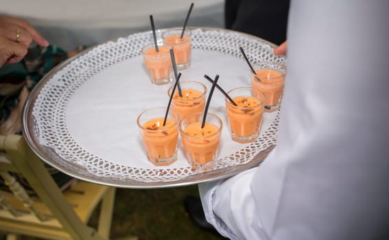 Waiter offering gazpacho and salmorejo shots. Selective focus