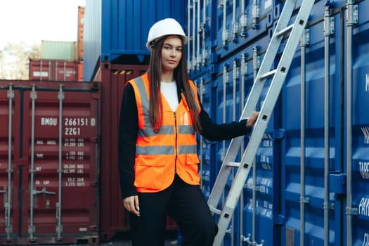 Woman Engineer with a Construction Ladder at Shipping Containers Terminal. Safety precautions