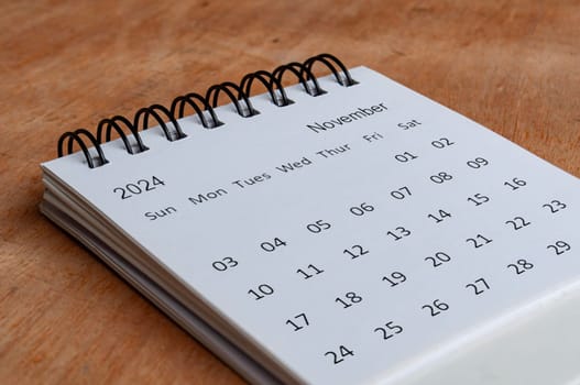November 2024 white table calendar on wooden background. Calendar concept
