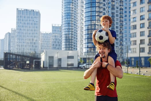 Portrait of father and son football player posing with soccer ball. Happy parenting and childhood concept