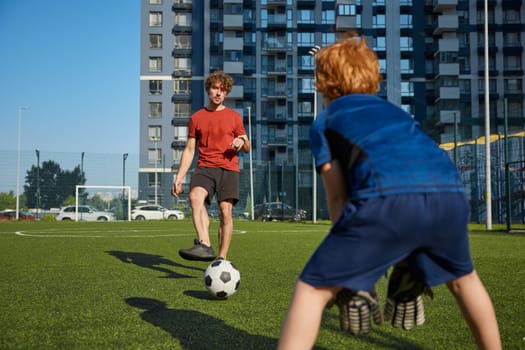 Dad with his little cute son playing football practicing game at city stadium. Active family and soccer sport