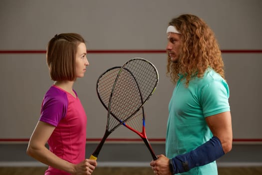 Male and female squash player confrontation on court concept. Man and woman in professional sport equality concept