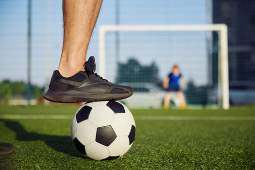Happy family playing football on field. Focus on father foot on soccer ball. Dad preparing to hit goal, son defending gate