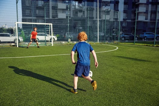 Father and son playing football training on pitch during sunny summer day. Family weekend sports activity