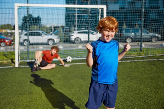 Happy son scored goal to his father celebrating win with clenched fist. Portrait of rejoicing boy child grimacing face