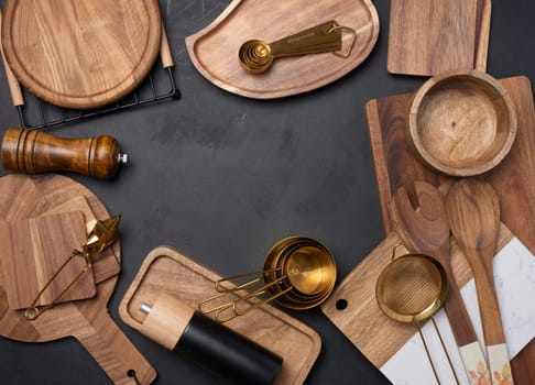 Various wooden kitchen utensils on black background, top view. Copy space