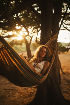 The girl swinging in the hammok on the seashore on the sunrise. beachtime.