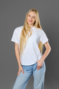 Blonde woman wearing blue jeans and white shirt posing in studio over grey background