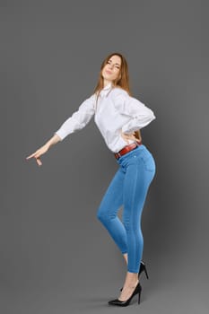 Naughty woman in white shirt and blue jeans pointing at something with her finger