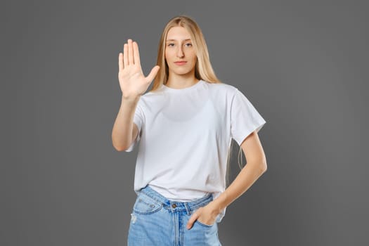 Serious young woman puts her palm forward in a stopping gesture