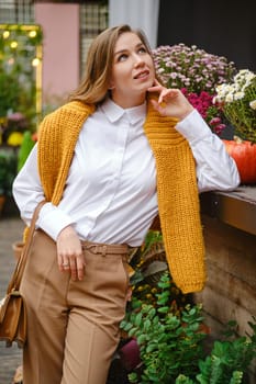 A dreamy woman stands among autumn plants and looks up