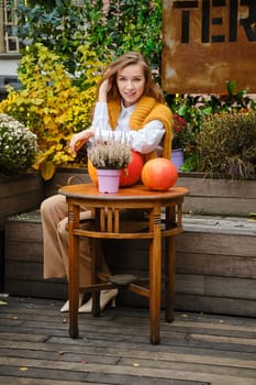 Street autumn portrait of a cute young woman among flowers and plants
