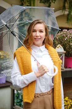 Portrait of a cute young woman with an umbrella at a flower fair