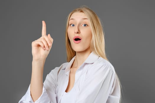 Young clever woman has found a solution and points her finger up to attract attention