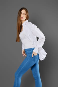 Brunette woman in shirt and jeans posing in the studio standing in profile
