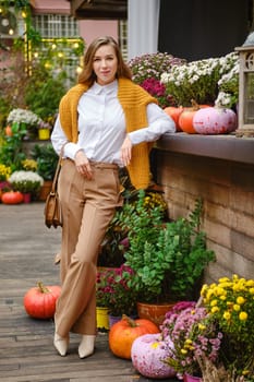 Outdoor portrait of a woman at an autumn fair leaning on a wooden display table