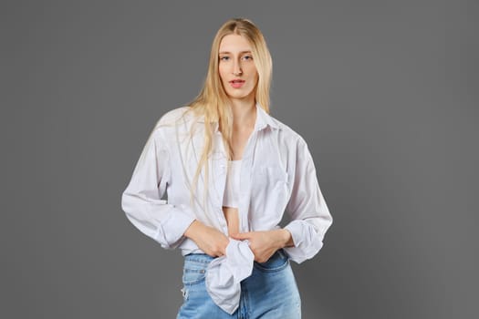 Stylish young blonde woman tying a shirt at her waist
