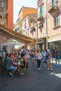 Taormina, Sicily, Italy - 28 September 2023. Tourists on the busy streets of the old town of Taormina in cafes and restaurants. City views, facades, architecture and the most popular streets.