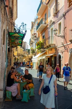 Taormina, Sicily, Italy - 28 September 2023. Tourists on the busy streets of the old town of Taormina in cafes and restaurants. City views, facades, architecture and the most popular streets.
