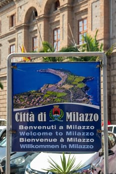 Milazzo, Sicily, Italy - 03 October 2023. Selective focus on the welcome sign in the centre of Milazzo with an outline map of the town area over blurred city Hall background.